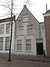 Pand onder zadeldak met gepleisterde puntgevel, waarin zes sierankers