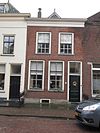 Pand onder schilddak, met voorgevel onder rechte lijst. Twee gietijzeren stoephekken