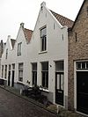 Pand onder zadeldak met aan voor- en achterzijde puntgevels. In de voorgevel een sieranker