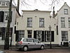 Pand met in de 19e eeuw gewijzigde gevel, die gepleisterd is en ingezwenkte zijkanten en een houten kroonlijst heeft