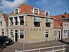Hoekpand met hoog schilddak, lijstgevel (XIX A) en achterbouw met oude kozijnen en luiken