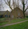 Zij-aanzicht dwarsgeplaatst voorhuis, achter het decoratieve hekwerk het inpandig melkhok