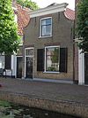 Pand met ingezwenkte gevel onder rechte lijst. IJsselsteen met rode vensterstrekken