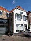 Huis met gepleisterde lijstgevel en in de verdiepingen oude kozijnen