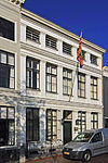 Pand achter monumentale gepleisterde gevel van parterre, verdieping en attiekverdieping