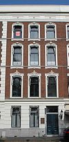 Met de nrs 20-21-23 a-b, 24-25-26 a-b als een monumentaal geheel opgevatte reeks panden, in eclectische trant met in pleister gebosseerde parterrevensters met stucversieringen, geblokte hoekkettingen in pilasters en attiek op de kroonlijst