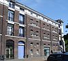 Onderdeel van een reeks pakhuizen. Lijstgevel met getoogde vensters en cordonlijsten