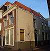 Pand met verdieping en pannen schilddak, dat aan de achterzijde aansluit tegen een puntgevel