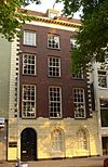 Koopmanshuis. Eenvoudige lijstgevel met gebosseerde pui en hoekkettingen. In de pui getoogde vensters en deur. De vensters van de bel-etage en de verdiepingen hebben 18-12- en 9-ruitsschuiframen