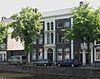 Herenhuis met lage bovenverdieping en lijstgevel, waarvan de middenas een rijke stucwerkversiering heeft. Getoogde vensters. Gang met stucplafond
