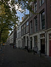 Pand met eenvoudige lijstgevel. In de parterre twee getoogde deuromlijstingen met authentieke, gesneden deur met fraai gesneden bovenlichten in Lod. XVI-trant. Stoep met stoeppalen