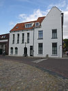 Pand met lijstgevel, waarvan de deuromlijsting gesneden versieringen en een gesneden kalf bezit