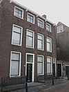 Dwarshuis van parterre en twee verdiepingen onder zadeldak. Gootlijst op gesneden Lodewijk XIV-consoles. Hardstenen vensterdorpels. Breedte vier vensterassen