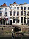 Pand onder schilddak. Gepleisterde voorgevel met stucornamenten en lijst met consoles