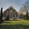 Gezicht op voorgevel met ingangspartij, houten geveltop met makelaar
